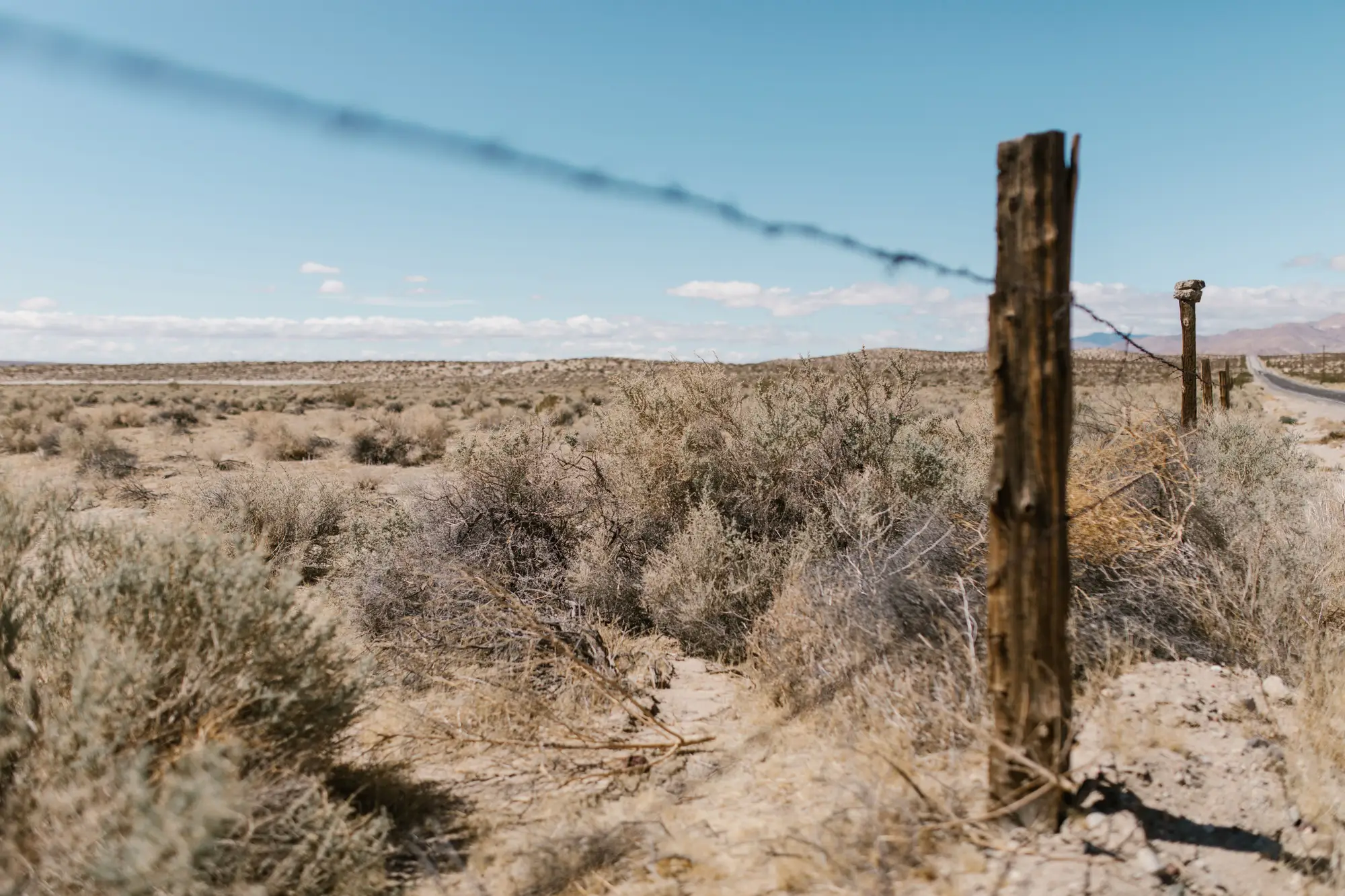 A weathered wooden fence post and wire in dry sagebrush country